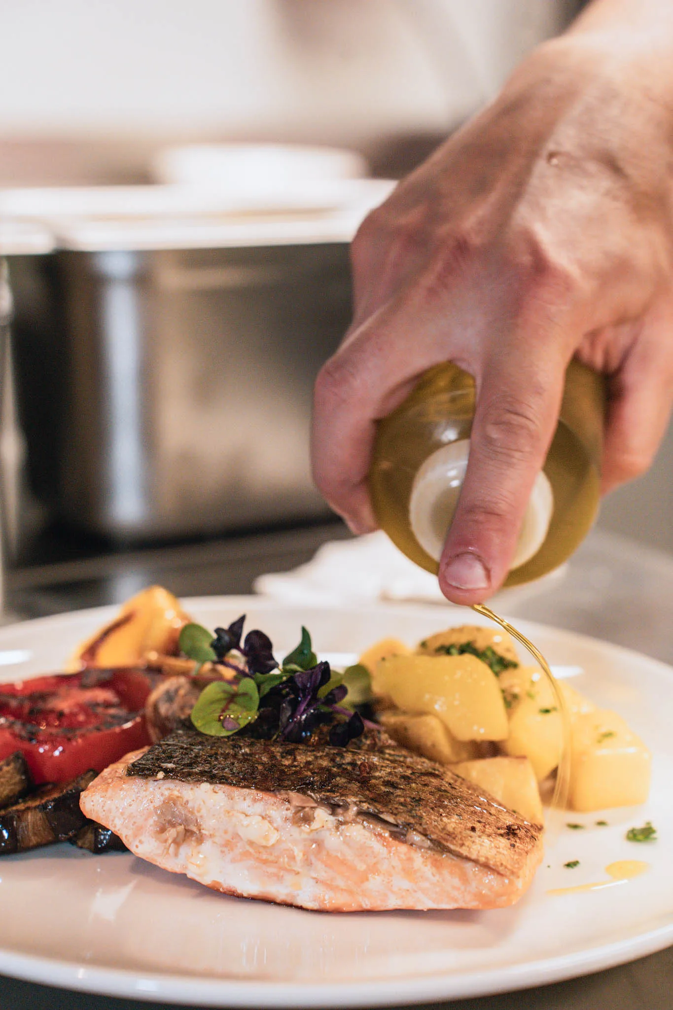 Lachsfilet mit Kartoffeln und Grillgemüse, Olivenöl wird darübergegossen
