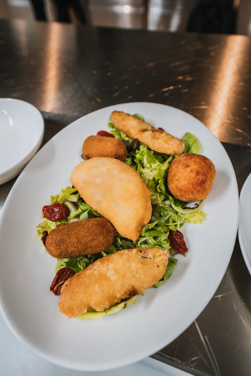 Fritti misti: crocchette, panzerotti e arancini su insalata